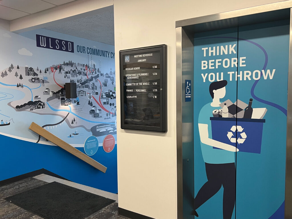 WLSSD lobby design with 'Our Community Cycle' wall mural and elevator graphics, design by Šek Design Studio